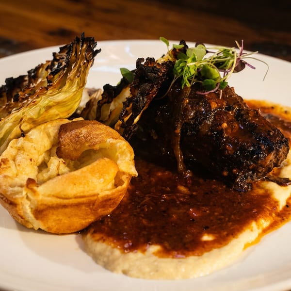 Braised short rib with gravy, mashed potatoes, roasted cabbage, and a Yorkshire pudding.